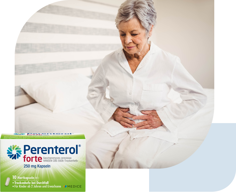 Eine Perenterol forte Verpackung, mit einer Frau mit Magenbeschwerden im Hintergrund