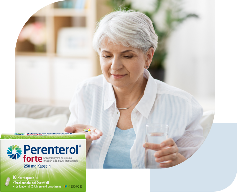 Eine Perenterol forte Verpackung, mit einer älteren Damen, die Tabletten nimmt im Hintergrund