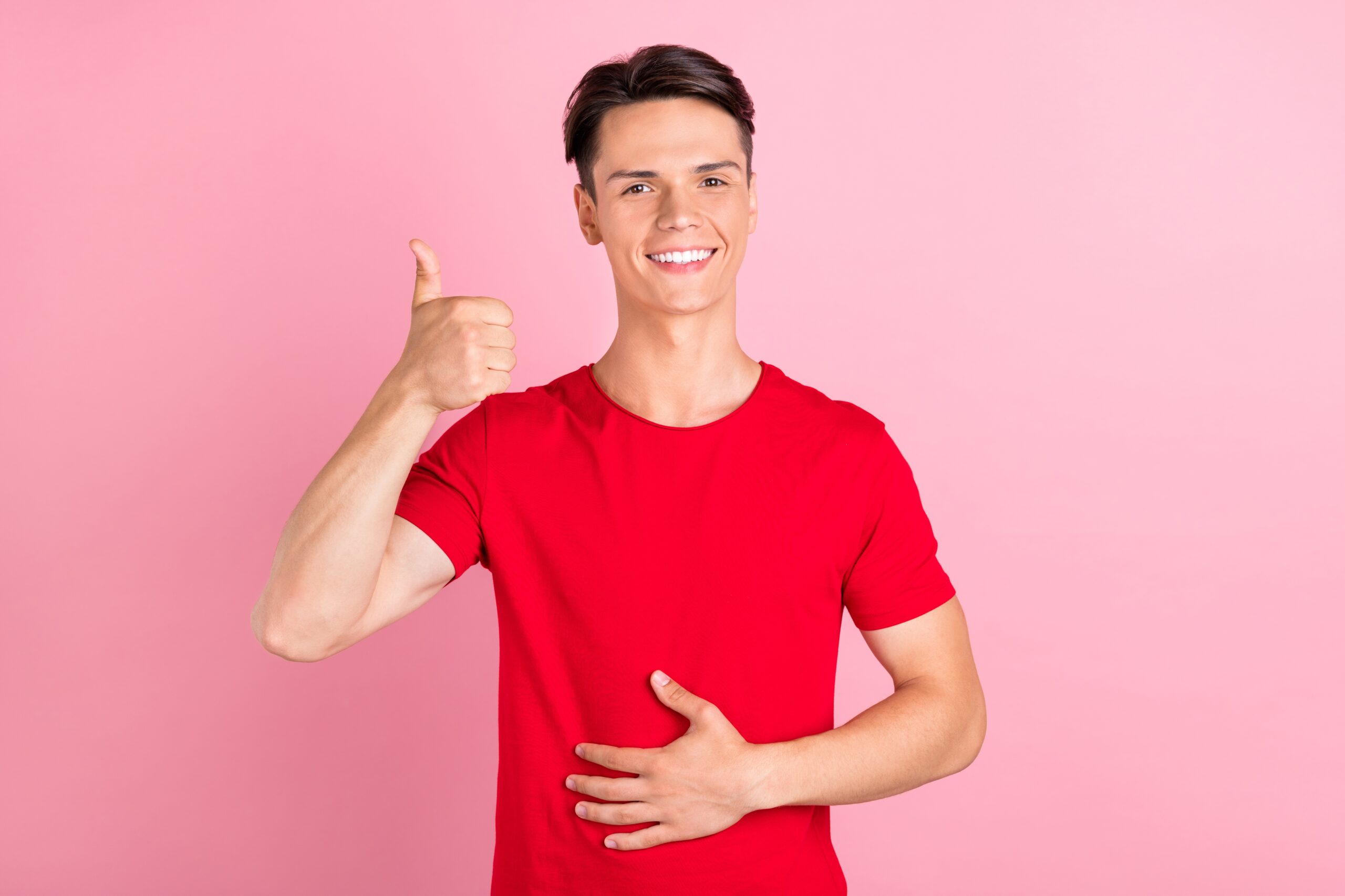 Ein junger Mann, der trotz Magenbeschwerden lächelt