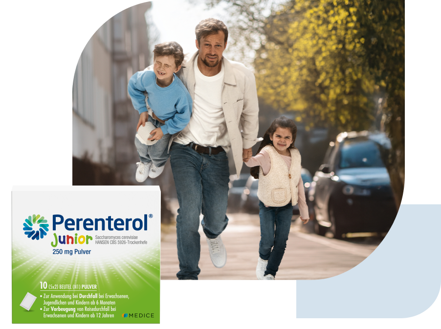 Eine Perenterol junior Verpackung, mit einem rennenden Vater und zwei Kindern mit Magenbeschwerden im Hintergrund